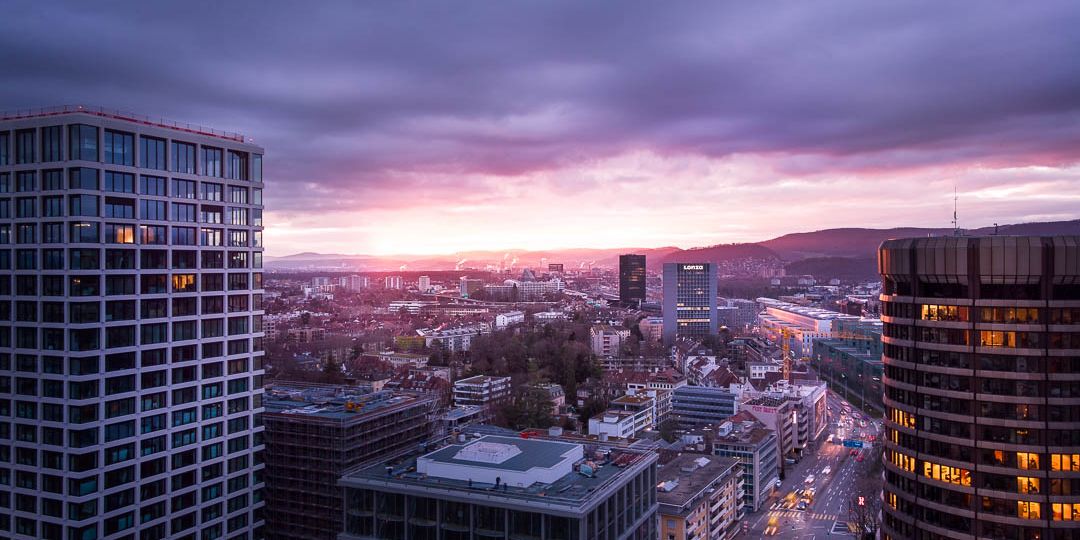 Drone photograph of a sunrise between baloise park and BIZ tower in Basel